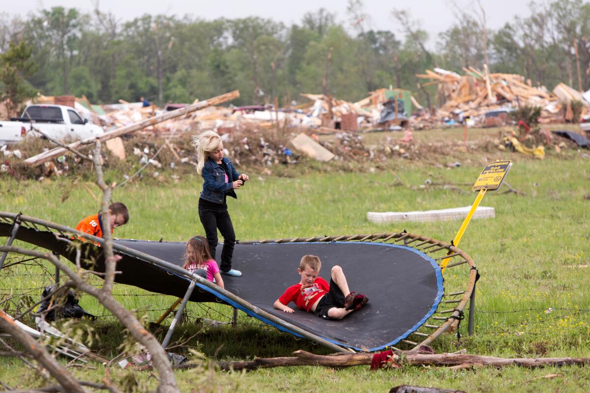 Children play on a mangled trampoline near the home of their grandparents, Gayla and Gary Evatt, who lived off Naylor Road in Vilonia, Ark.