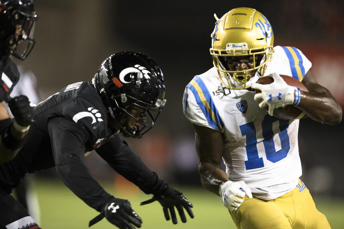 Cincinnati safety Darrick Forrest, left, forces UCLA running back Demetric Felton out of bounds during the second half of the Bruins' loss on Thursday.