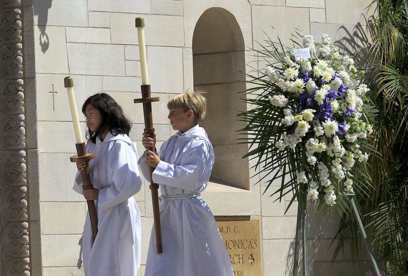 An altar girl and altar boy walk into St. Monica Catholic Church.