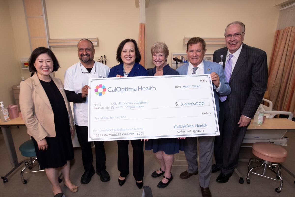 CalOptima Health leaders present Cal State Fullerton with a ceremonial check.