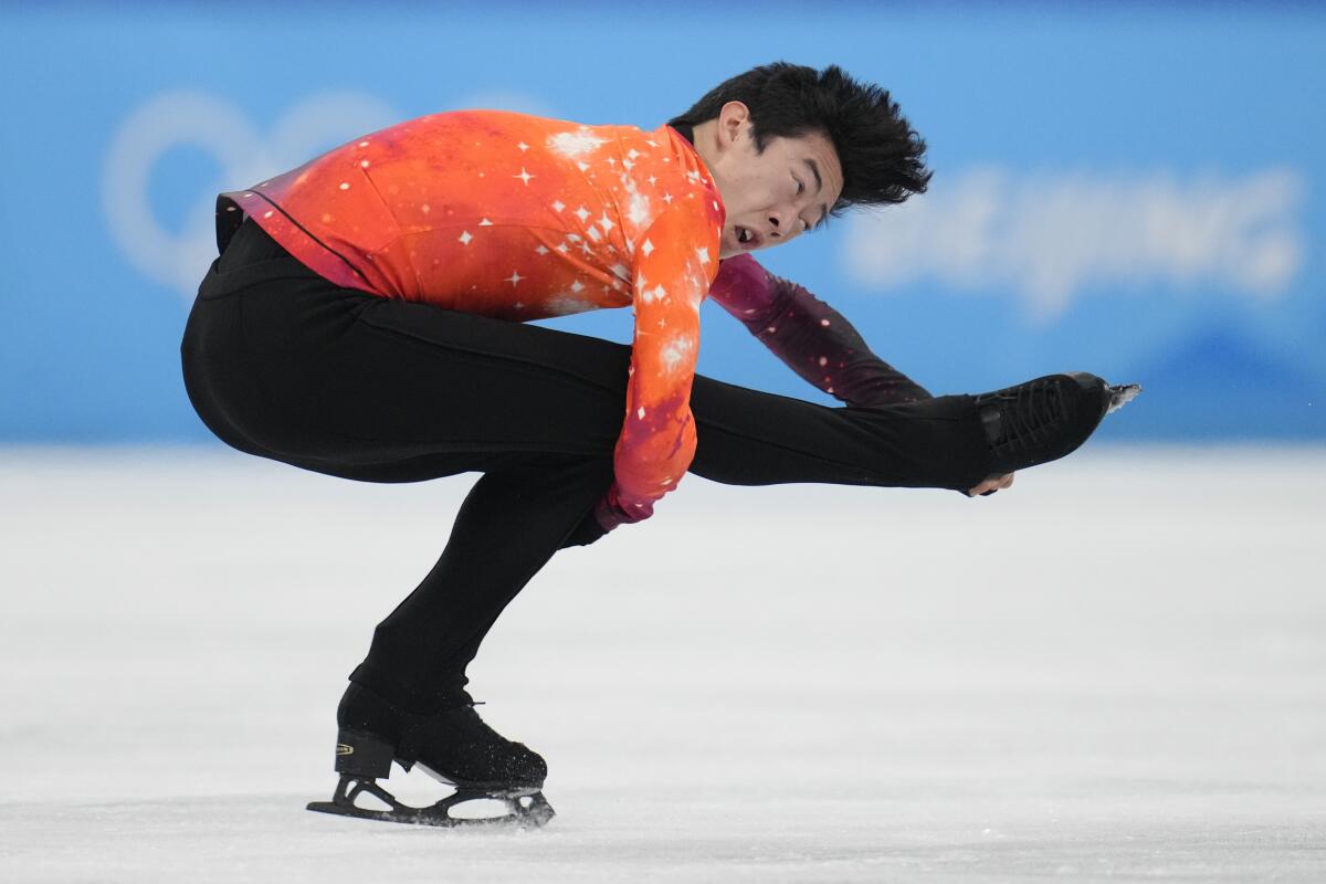 A man grabs his leg as he performs a sit-spin on the ice.