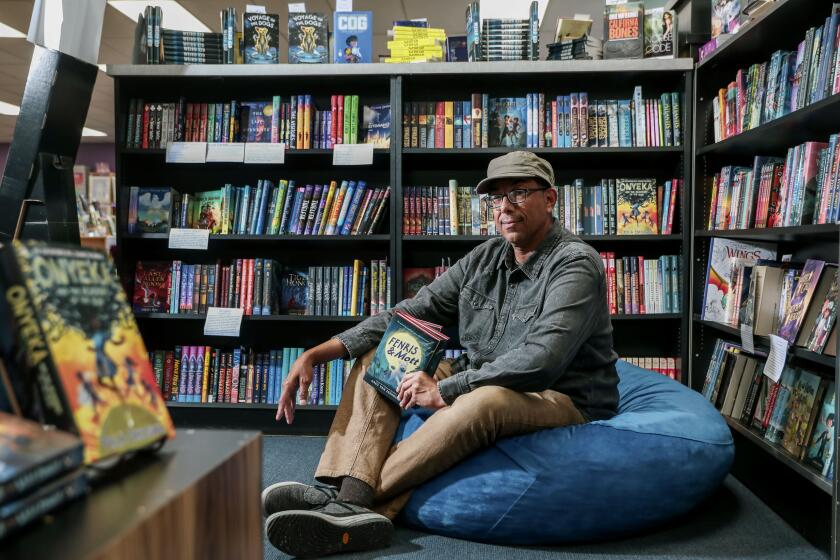 SAN DIEGO, CA JULY 25: Pacific Beach author Greg Van Eekhout sits with his new book "Fenris & Mott," at Mysterious Galaxy Bookstore on Monday, July 25, 2022. Greg is the award-winning author of several middle-grade novels.. (Photo by Sandy Huffaker for The San Diego Union-Tribune)