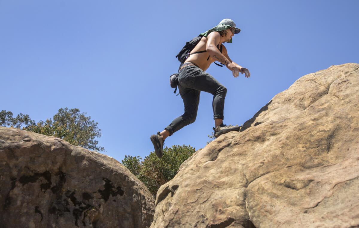 Colter Johnson of Santa Monica protects his head from the blazing sun while climbing sandstone rocks at Stoney Point Park in Chatsworth.