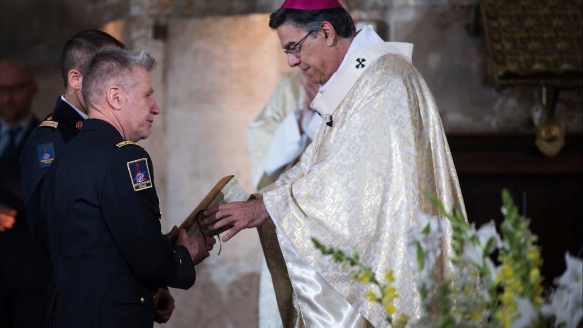 Archbishop of Paris Michel Aupetit gives a Bible saved from the flames at the Notre Dame Cathedral to the French general firefighter Jean Claude Gallet during a Mass in tribute at the Saint Eustache Church in Paris on Sunday.