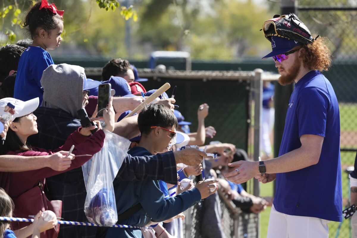 Dodgers pitcher Dustin May, right, signs autographs for fans at Camelback Ranch on Feb. 20.