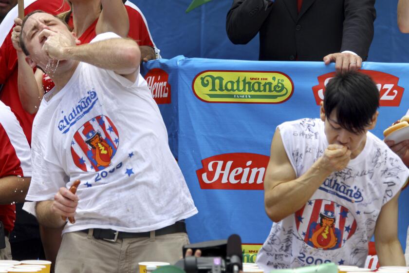 Joey Chestnut, campeón defensor del concurso de comedores de hot dogs Nathan's del 4 de Julio, a la izquierda, compite contra el excampeón Takeru Kobayashi, el 4 de julio de 2009, en Nueva York. (AP Foto/Craig Ruttle, Archivo)