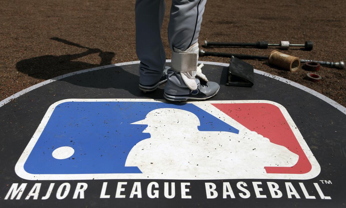 A player stands on the Major League Baseball logo that serves as an on-deck circle.