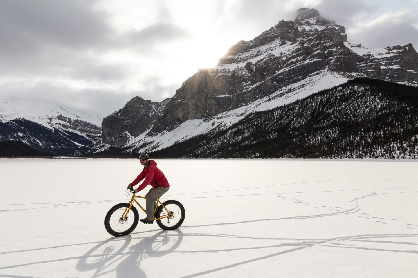 A man circles around a frozen lake on his fat bike in Jasper, Canada.