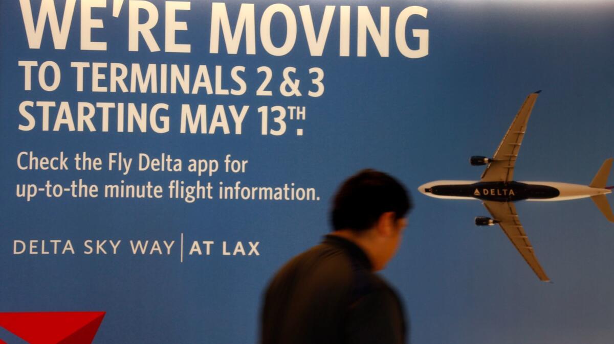 A man walks by a poster that announces a relocation by Delta Airlines, in one of the largest terminal moves in history. It begins Friday night.