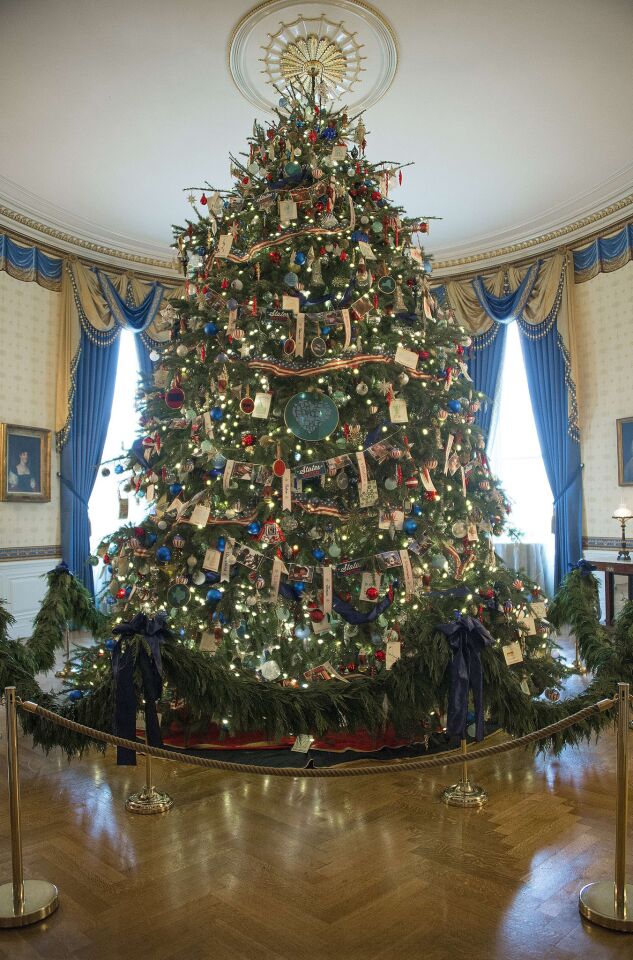 Decorations honoring military families hang on the official White House Christmas tree in the Blue Room at the White House this holiday season.