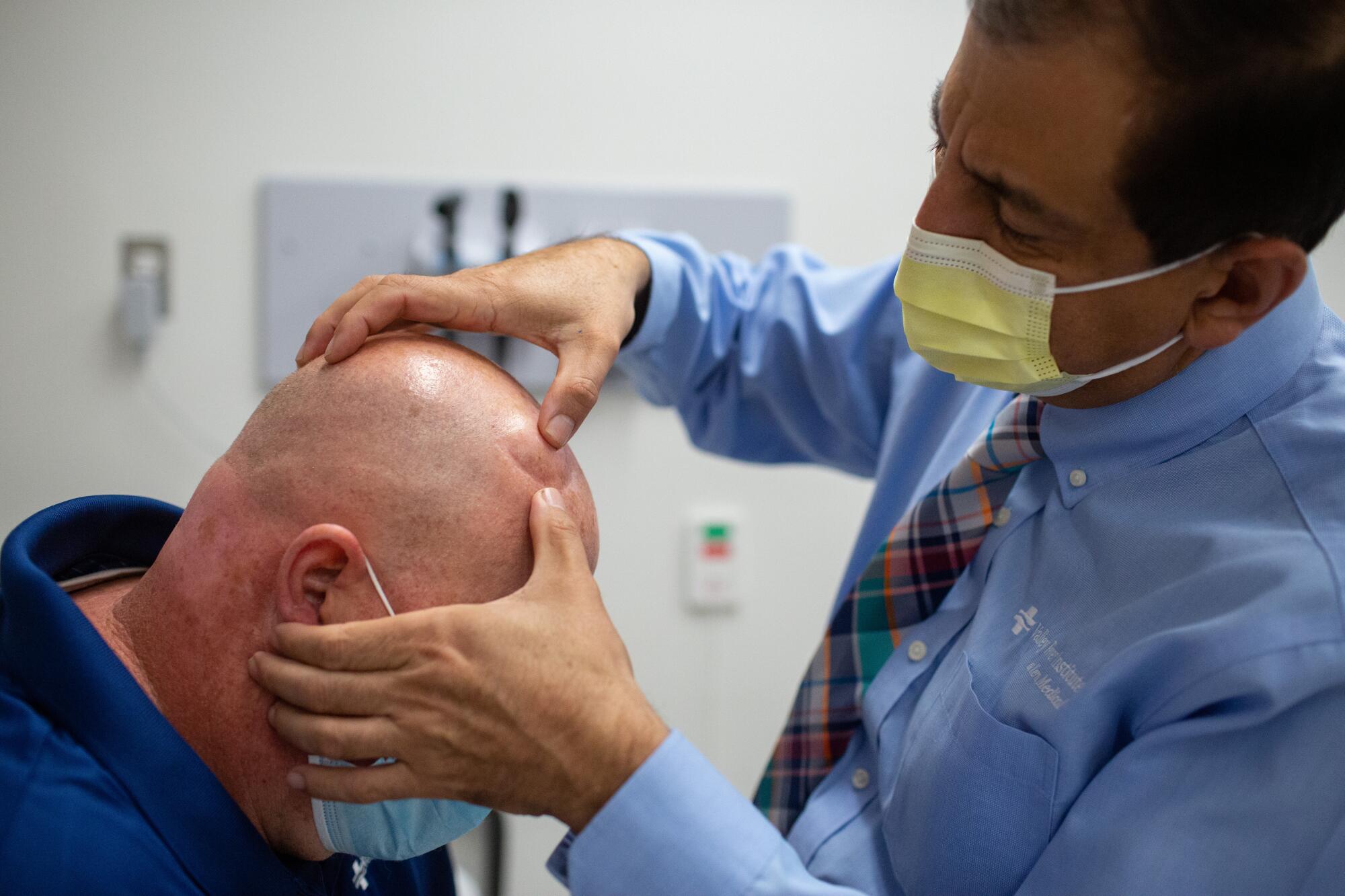 A physician examines the port on a man's head that is used to deliver medicine to treat his Valley fever.