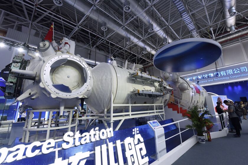 In this Nov. 7, 2018, photo, visitors look at a life-size model of the Tianhe core module of China's next space station at the Airshow China in Zhuhai in southern China's Guangdong Province. China on Thursday, June 17, 2021 has launched its first crewed space mission in five years, sending three astronauts to a new space station that marks a milestone in the country's ambitious space program. (Chinatopix via AP)