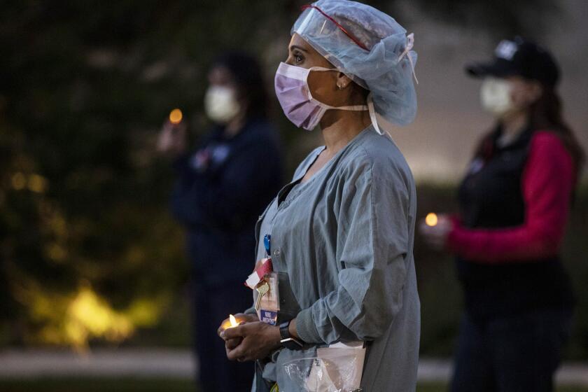 Nurse anesthetist Nilu Patel quietly stands with fellow nurses at UC Irvine Medical Center for an hour long candlelight vigil at their shift change. They describe conditions and the need for more N95 respirators and protective gear required to safely treat coronavirus patients. (Robert Gauthier / Los Angeles Times)