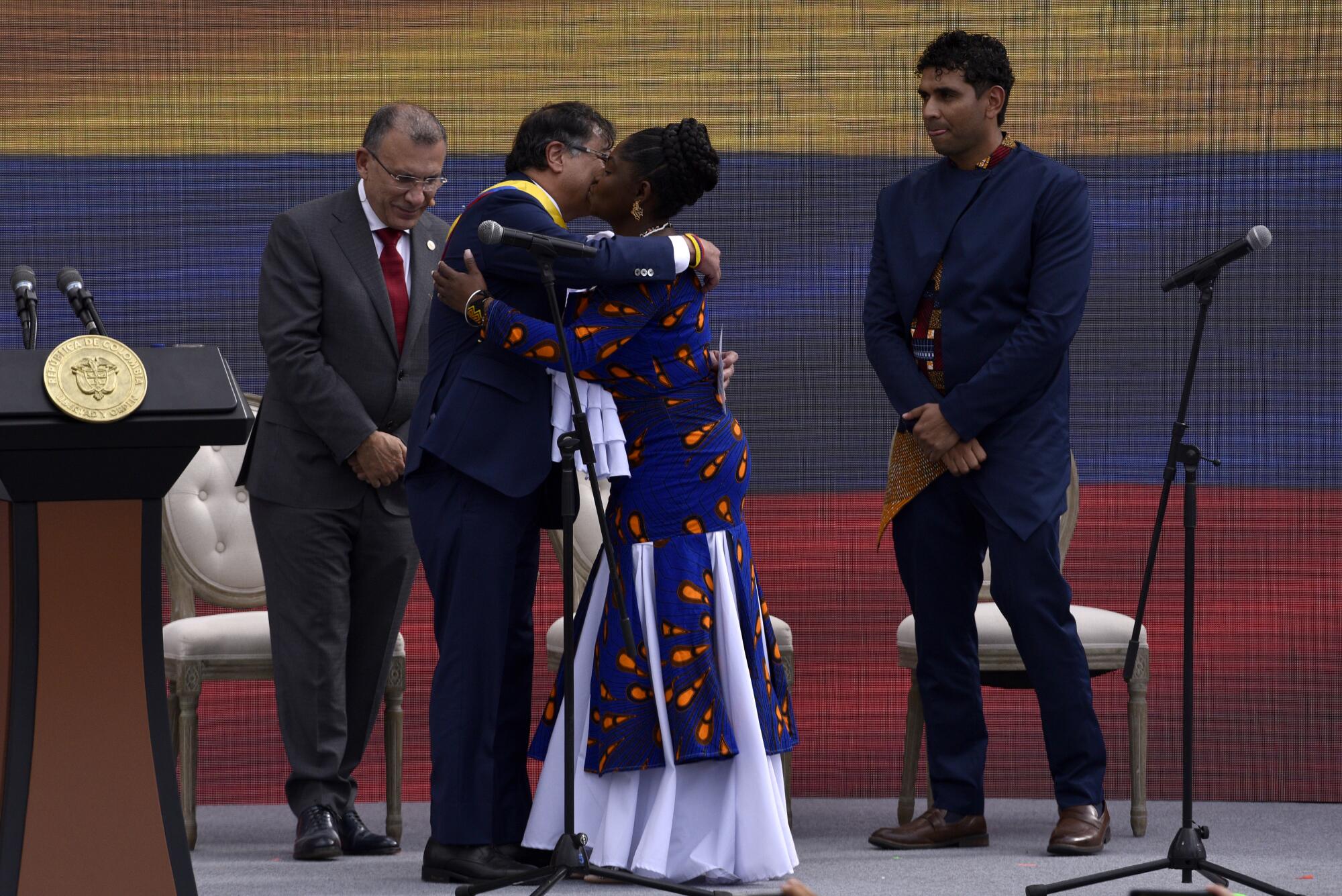 A man and woman embrace on stage while two other men stand by. 