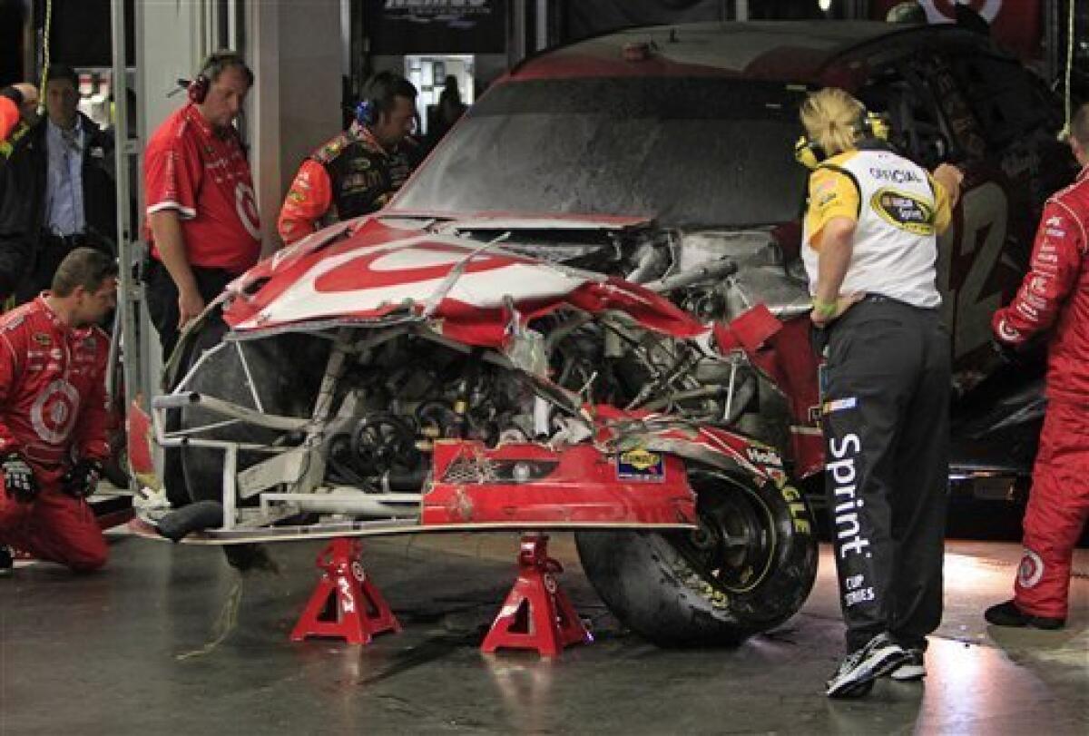Crew members and a NASCAR official check out the damage to Juan Pablo Montoya's car after it collided with a track dryer during the NASCAR Daytona 500 auto race at Daytona International Speedway in Daytona Beach, Fla., Monday, Feb. 27, 2012. (AP Photo/John Raoux)