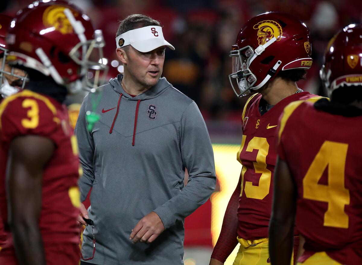 USC coach Lincoln Riley talks with quarterback Caleb Williams and his teammates on the sideline before a game