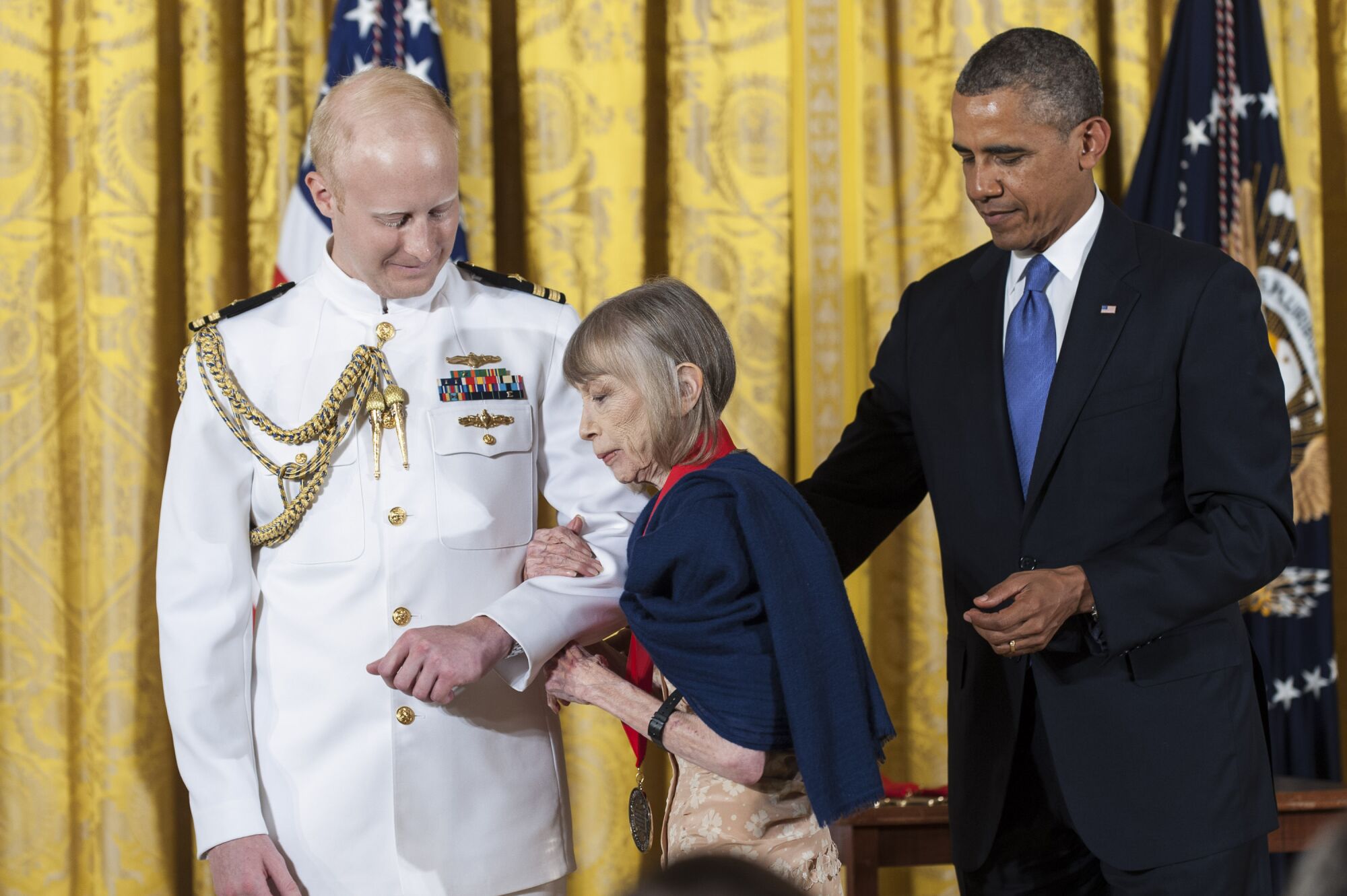 A uniformed official escorts Joan Didion as President Obama looks on.
