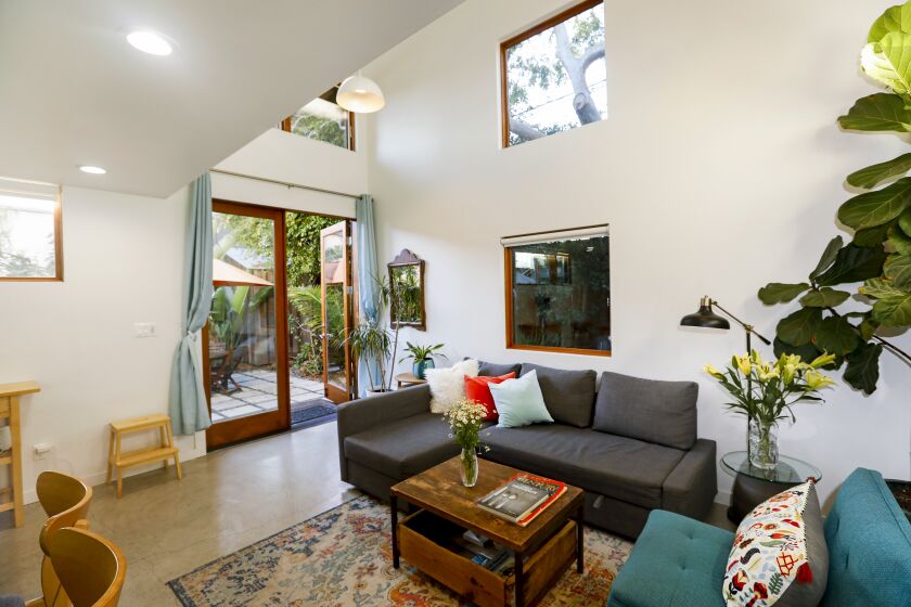 Los Angeles, Mar Vista, California-Feb. 4, 2022-This two-story 650 square-foot Accessory Dwelling Unit (ADU) in Mar Vista designed by architect Isabelle Duvivier features a private entrance, patio and garden that brings the outdoors in without sacrificing privacy. The double height living room has 18 foot ceilings which makes the tiny space feel really spacious. There are raised windows (to maximize privacy/ light) in every room that look on to the trees and X- large French doors going out to a private garden and outdoor eating space. Kitchen is Ikea, with tiny appliances, 24 inch oven, sink, etc. Upstairs there are two small rooms, one with a half wall looking down on the living area, and the other full enclosed. Isabelle Duvivier designed the ADU for her sister Chantal de Renesse who rents it out as an AirBnb to supplement her income. (Carolyn Cole / Los Angeles Times)