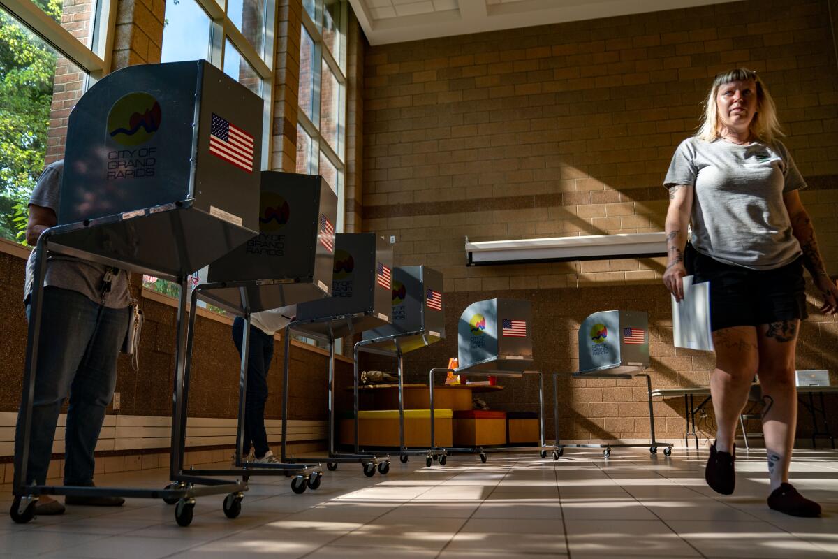 A person walking in a room with voting booths