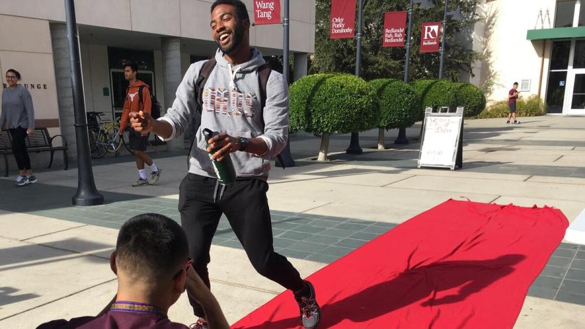 University of Redlands senior Marcus Garcia, left, takes a social media video of senior Afari La-Anyane walking down a DUDES runway event.