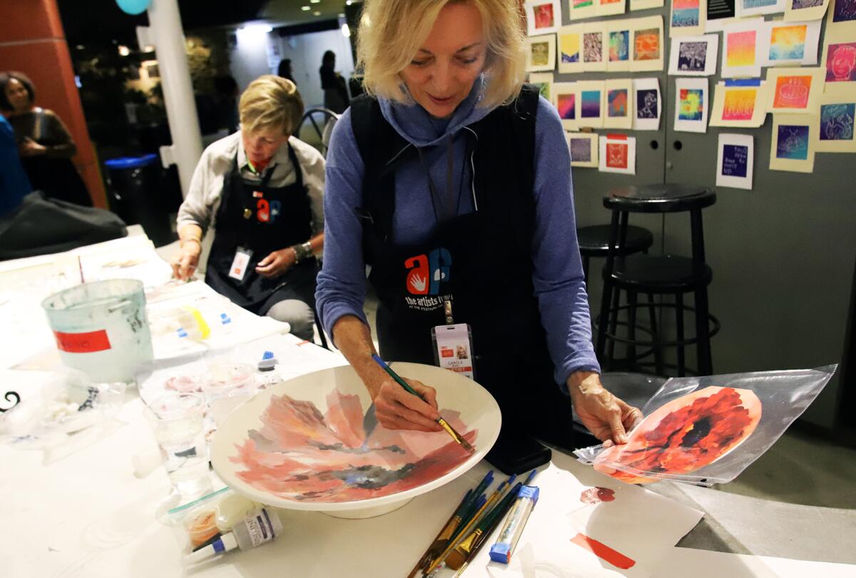 Carole Boller of Laguna Beach paints her platter "I'm in the Red" during the Platter Painting Party.