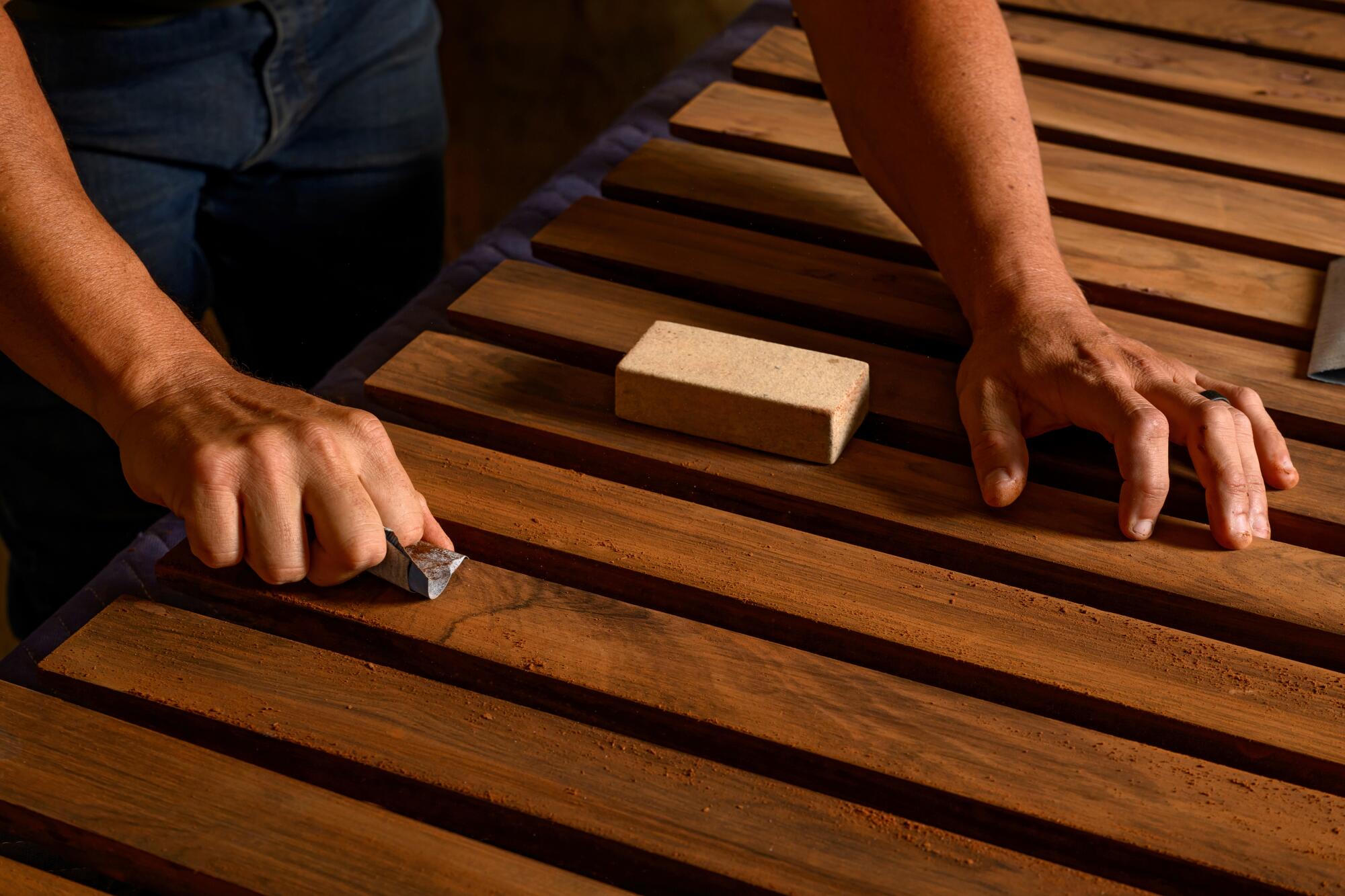 A pair of hands shown working on a wood-based project.