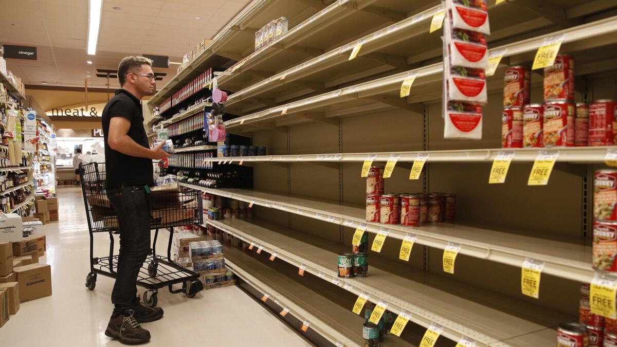 A worker looks at the empty shelves of canned goods at a supermarket ahead of Hurricane Lane in Honolulu.