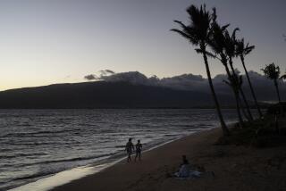 A couple walks along the beach in Kihei, Hawaii, Thursday, Aug. 17, 2023. Long before a wildfire blasted through the island of Maui the week before, there was tension between Hawaii's longtime residents and the visitors some islanders resent for turning their beaches, mountains and communities into playgrounds. But that tension is building in the aftermath of the deadliest U.S. wildfire in more than a century. (AP Photo/Jae C. Hong)