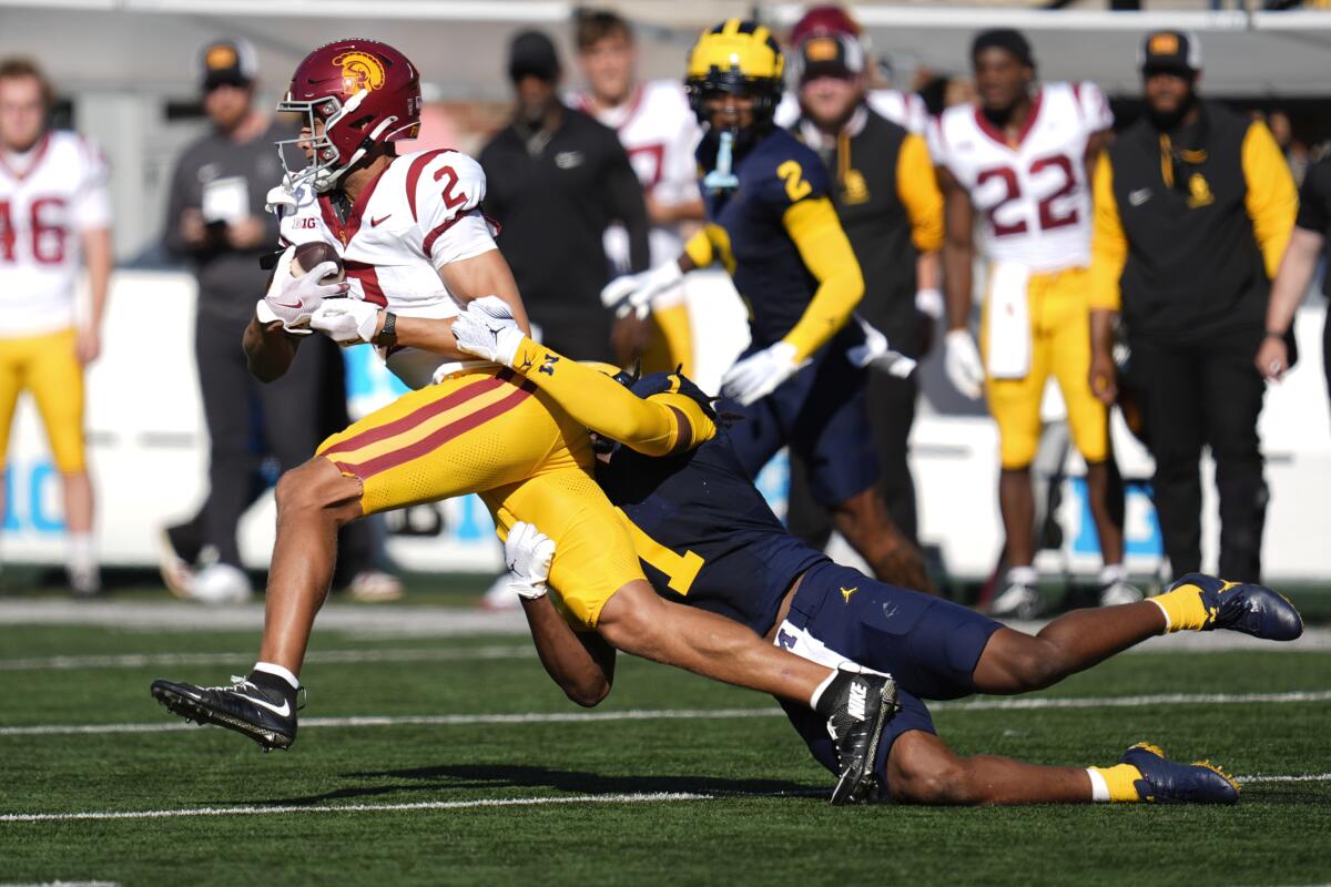 USC receiver Duce Robinson is tackled from behind by Michigan linebacker Jaishawn Barham 