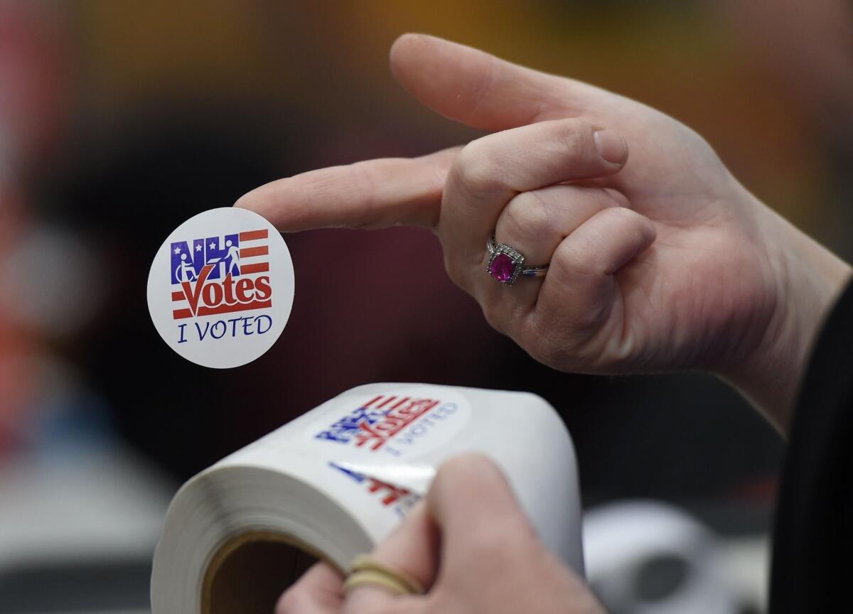 An election worker hands out stickers to voters afer they cast their ballots in Belmont, N.H.