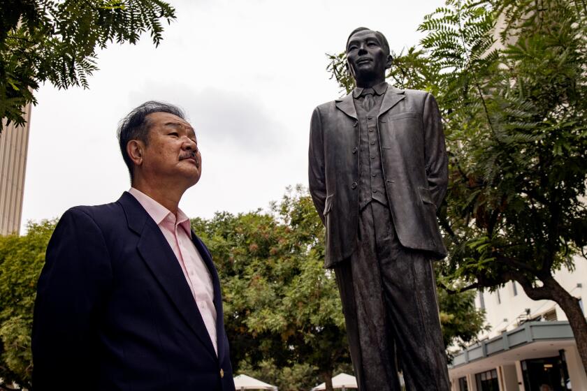 RIVERSIDE, CA - OCTOBER 7, 2021: UC Riverside Professor Edward Taehan Chang stands near the statue of Dosan Ahn Chang Ho, who is the founding father for democracy at a historical koreatown called Pachappacamp on October 7, 2021 in Riverside, California. Pachappacamp no longer exists and is now an oil pumping site. Professor Chang has researched the now extinct Riverside Koreatown.(Gina Ferazzi / Los Angeles Times)