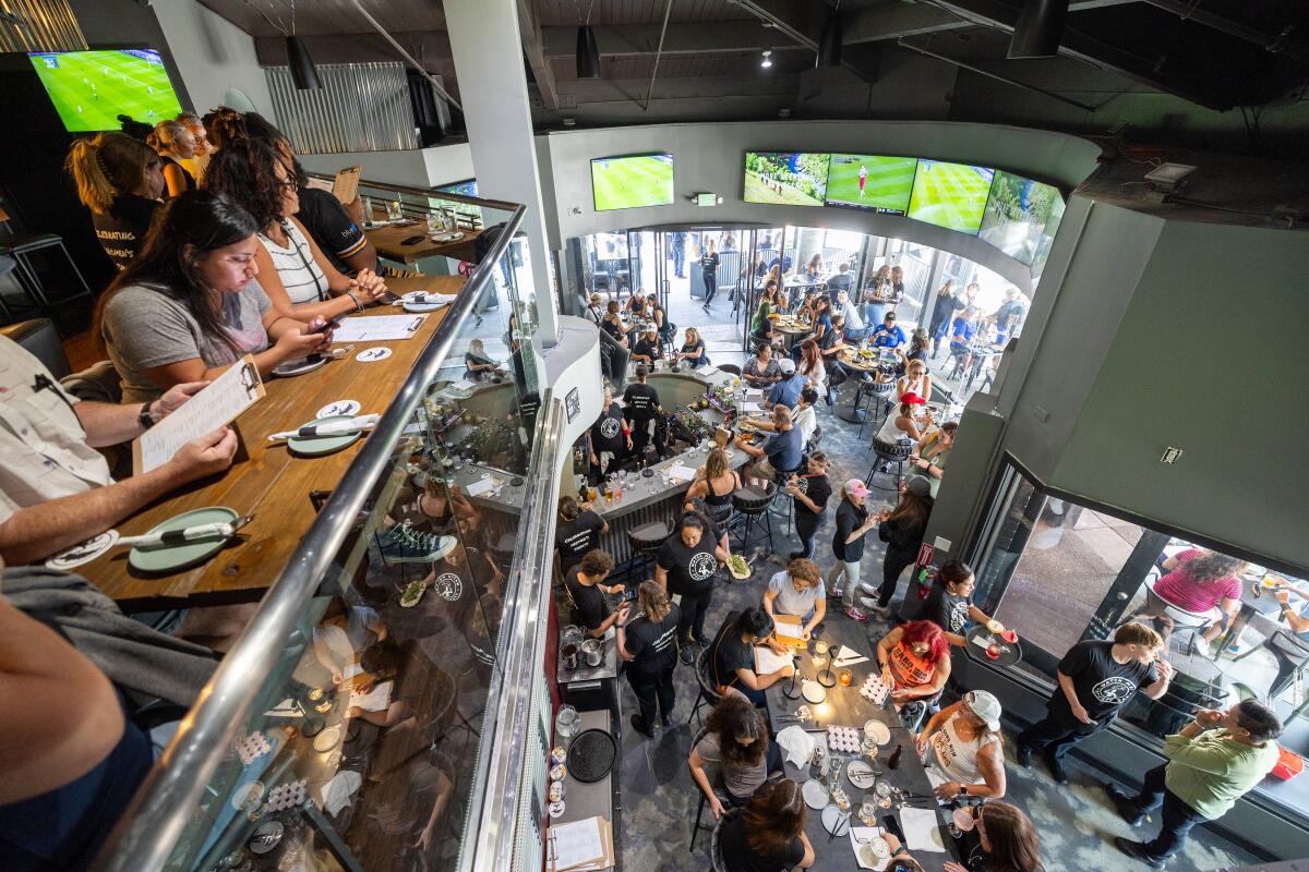 Patrons fill the bar, ordering food and drinks and watching women's sports during the grand opening of Watch Me! Sports Bar.