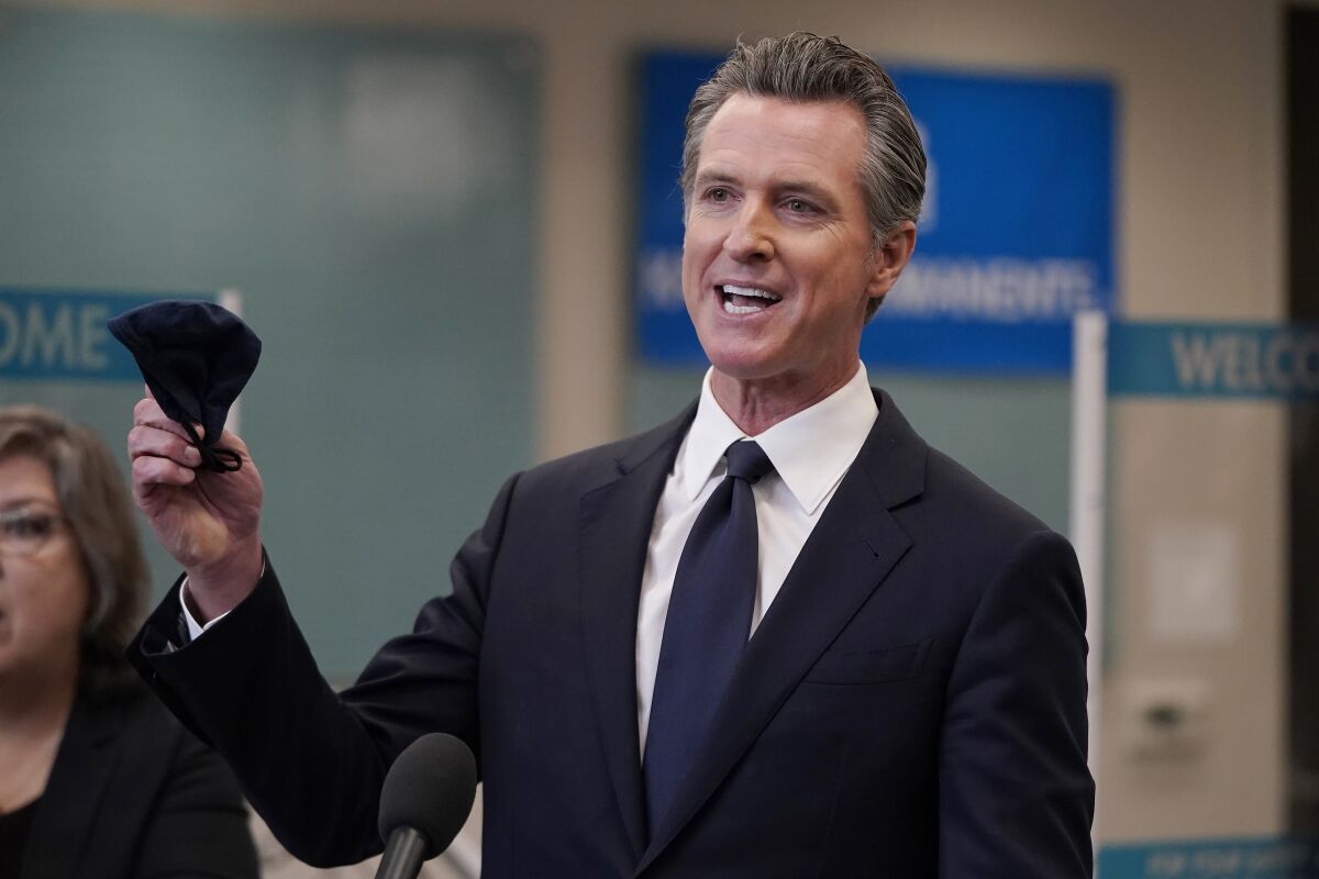 FILE- In this July 26, 2021 file photo Gov. Gavin Newsom holds a face mask while speaking at a news conference in Oakland, Calif. Newsom is facing recall election and his team trying to drive up Democratic turnout to keep him in office. (AP Photo/Jeff Chiu, File )