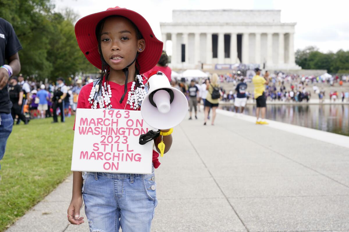 T'Kyrra Terrell, 6, holds a small bullhorn and a sign near the Lincoln Memorial.