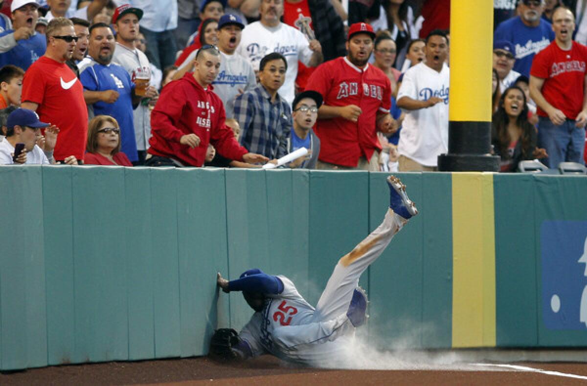 Dodgers left fielder Carl Crawford slides hard into the wall after catching a fly ball hit by Angels third baseman Alberto Callaspo.