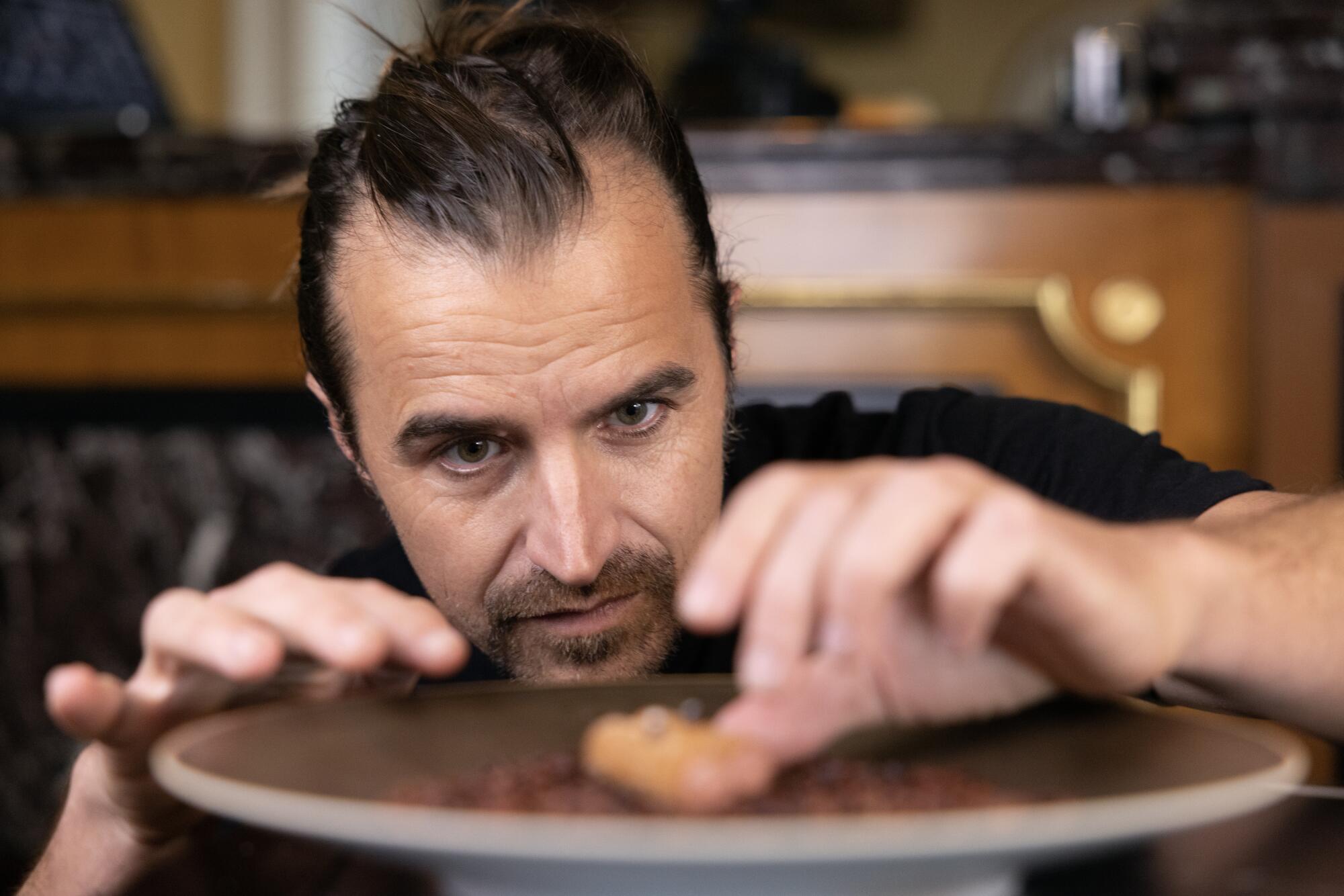 Food photographer Eric Wolfinger adjusts a chicken liver churro dish before shooting it.