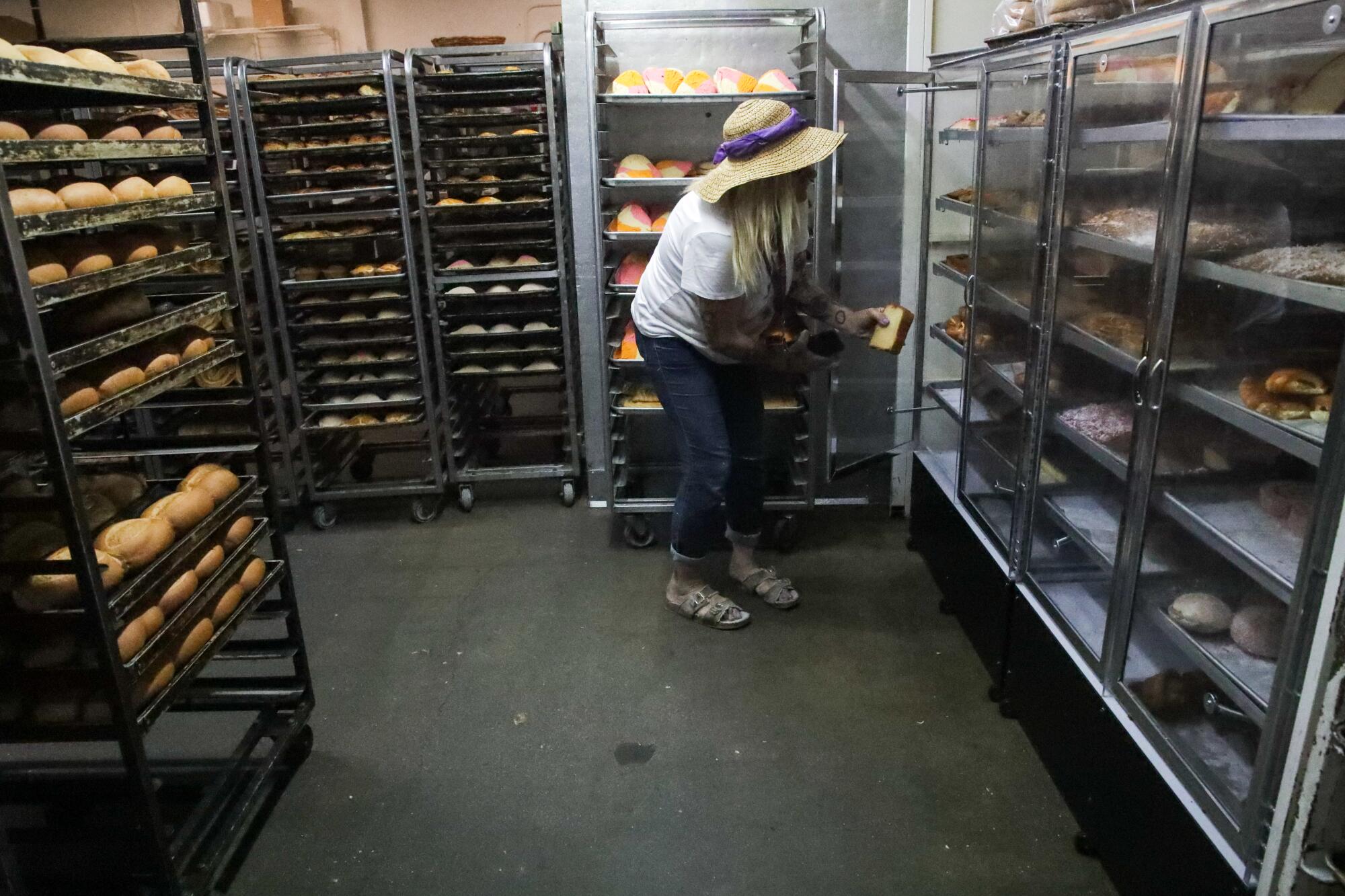 A person stands in a room surrounded by racks of pastry.