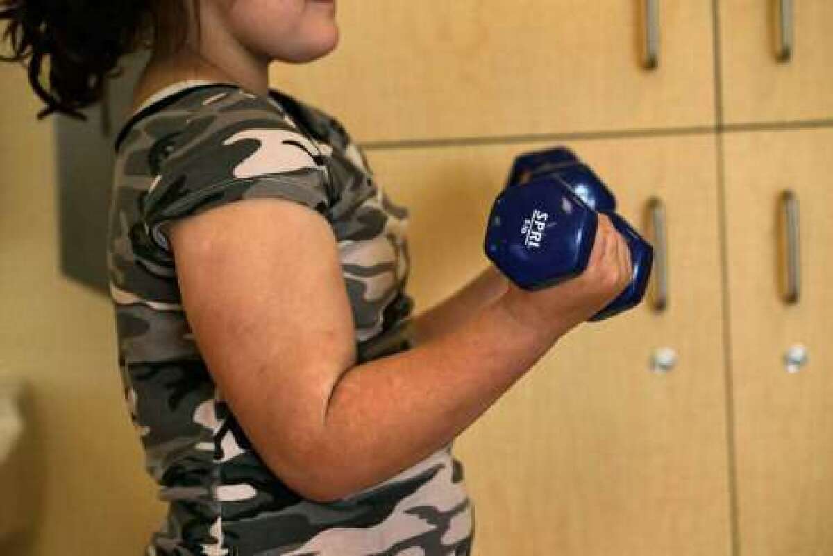 Parents may not recognize when their kids are overweight, a new poll suggests. Here, a 9-year-old exercises with weights.