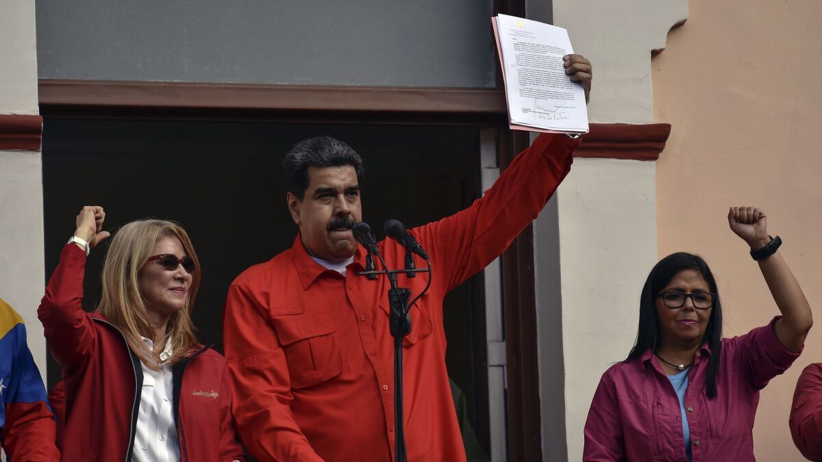 Venezuelan President Nicolas Maduro speaks to a crowd of supporters as he is flanked by his wife, Cilia Flores, left, and Vice President Delcy Rodriguez on Jan. 23, 2019.