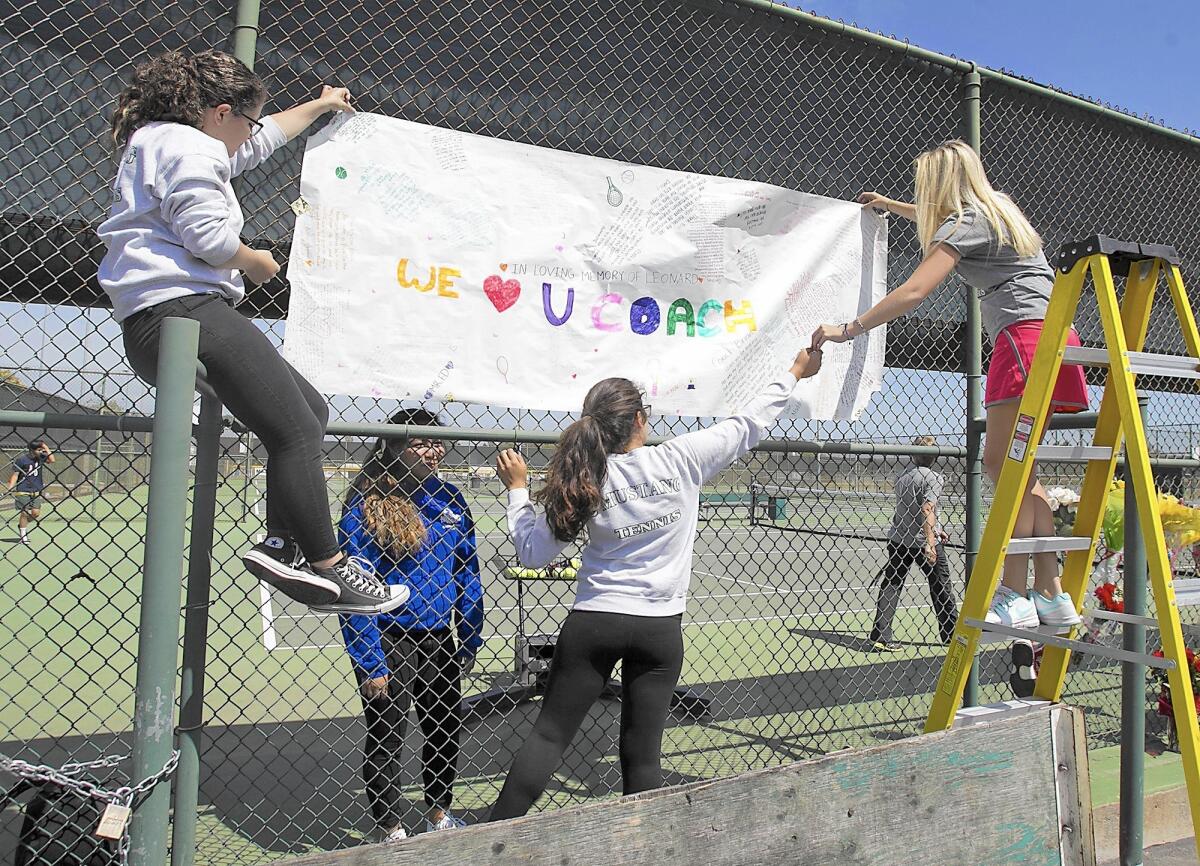 Members of the girls' Costa Mesa High School tennis team place a handmade banner in honor of coach Brian Ricker before a match on Tuesday afternoon.