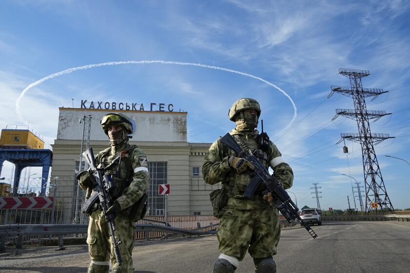 FILE - Russian troops guard an entrance of the Kakhovka Hydroelectric Station, a run-of-the-river power plant on the Dnieper River in Kherson region, southern Ukraine, May 20, 2022. The Kherson region has been under control of the Russian forces since the early days of the Russian military action in Ukraine. Russia and Ukraine have trade blame over shelling of the Zaporizhzhia nuclear power plant, Europe's largest.This photo was taken during a trip organized by the Russian Ministry of Defense. (AP Photo, File)