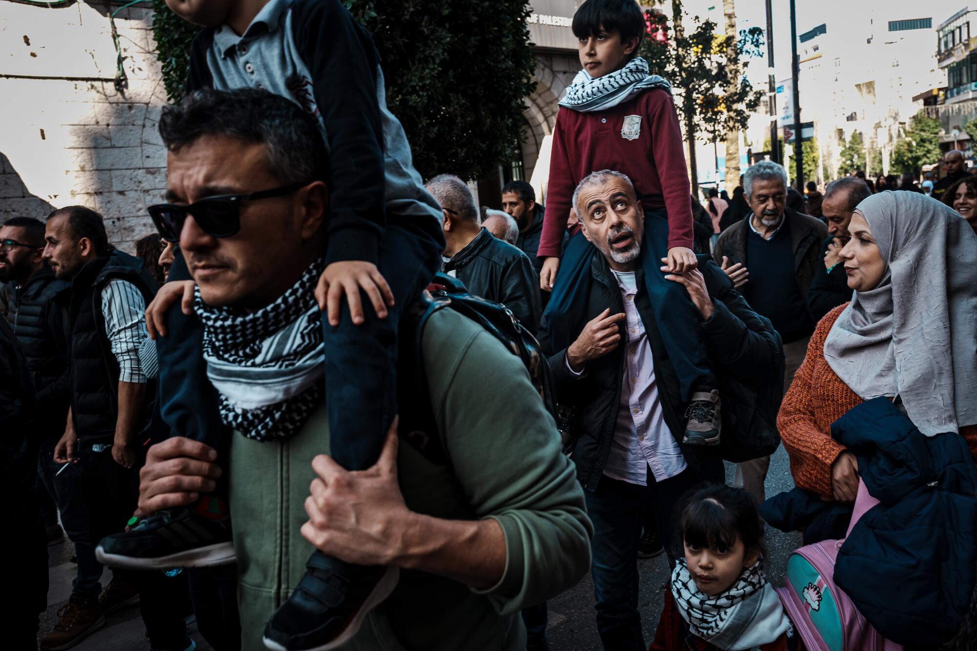 People march, some with children on their shoulders, during a demonstration.