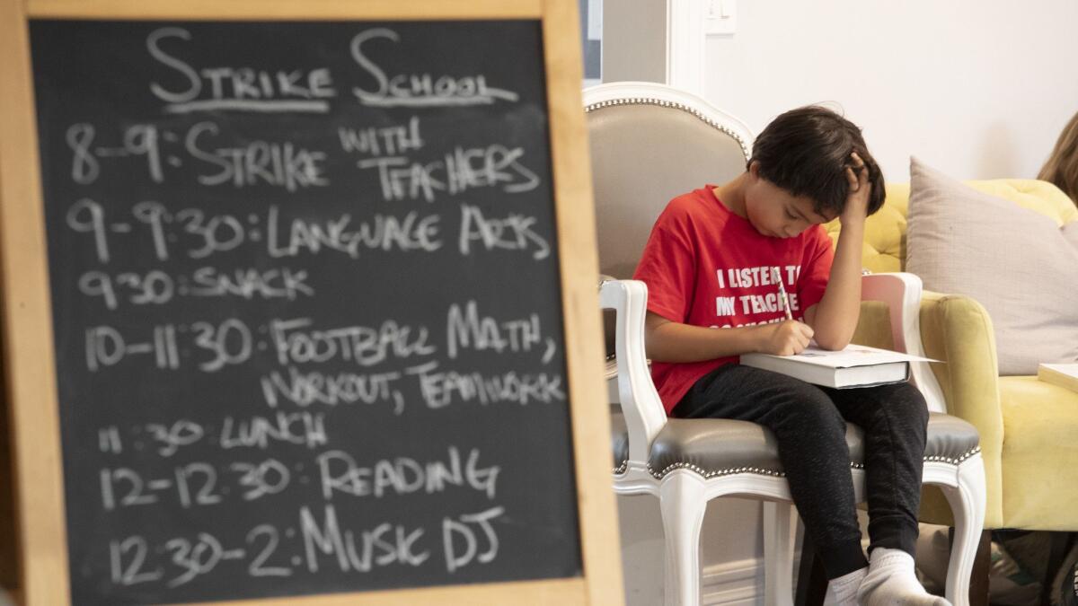 Encino Charter Elementary School student Gavin Hayes, 7, works on a math problem during "strike school" at the home of Corey Moss in Encino on Jan. 17. Parents are taking turns hosting kids in their homes and creating a curriculum.
