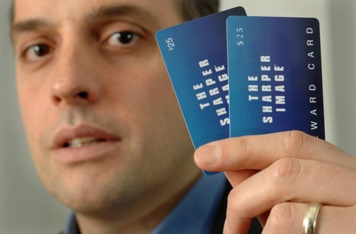 Jon Tapper holds a pair of unredeemable gift cards from bankrupt retailer The Sharper Image at his office in Boston.