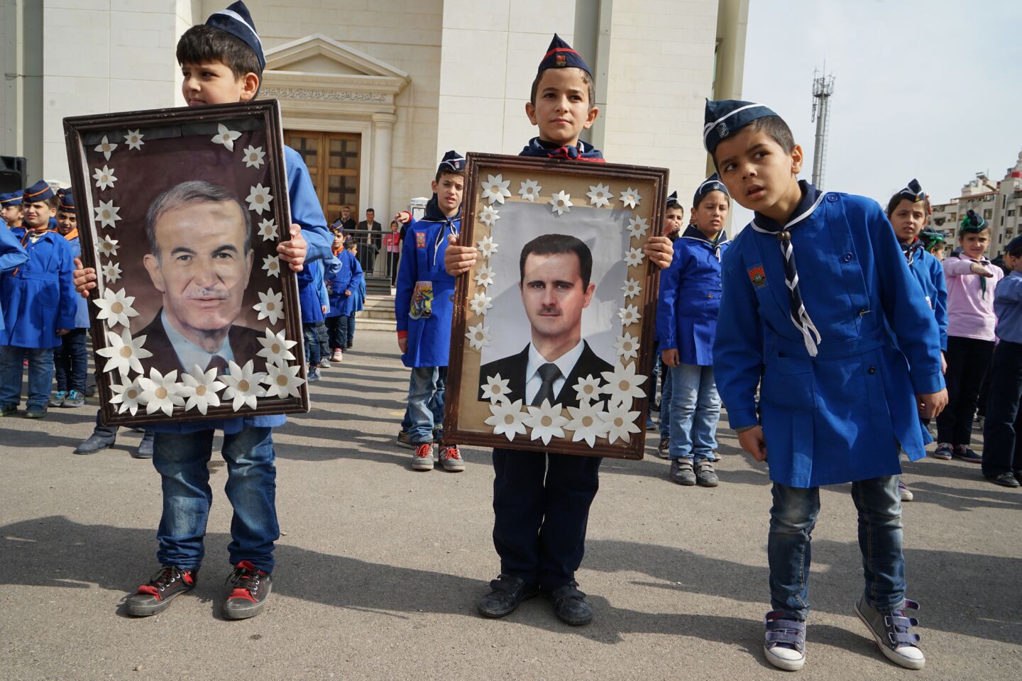 Elementary school children hold portraits of Syrian President Bashar Assad, right, and his late father, Hafez.