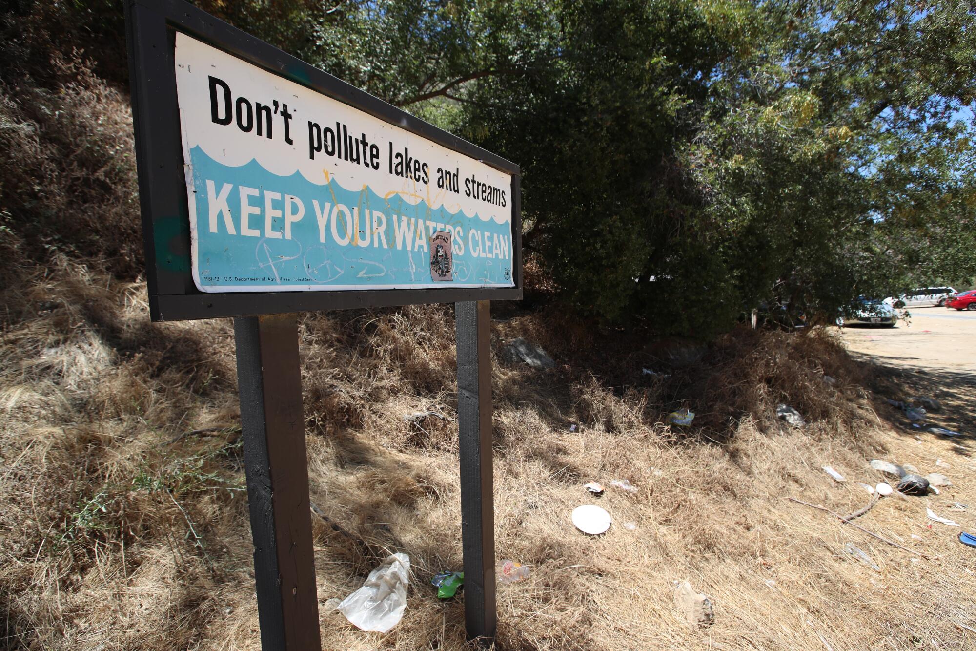 Litter surrounds a sign promoting environmental stewardship in San Gabriel Mountains National Monument.