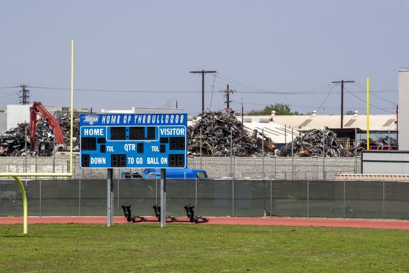 WATTS, CA - JUNE 16: An employee moves debris at Atlas Iron & Metal Co., which is a metal recycler that has piles of metal scrap and debris adjacent to Jordan High School Tuesday, June 16, 2020 in Watts, CA. (Allen J. Schaben / Los Angeles Times)