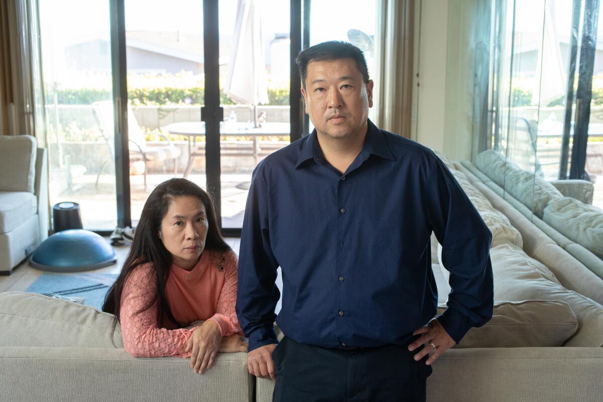 A woman looks over the back of a sectional where she is seated. A man stands next to her.