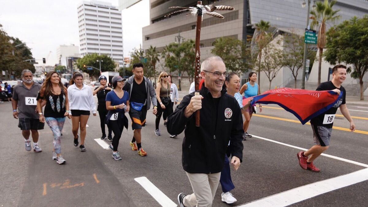 L.A. City Councilman Mitch O'Farrell holds the ceremonial running staff to start the 5K run in downtown Los Angeles for the first celebration of Indigenous Peoples Day.