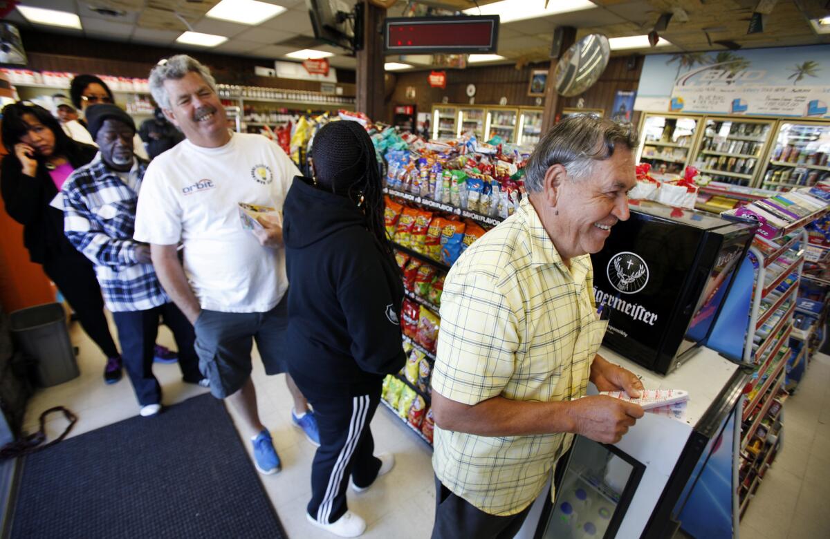 Rafael Moreno picks his lucky numbers as people form a line for Powerball tickets at Bluebird Liquor in Hawthorne.